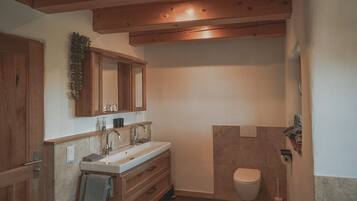 Un bagno con mobili in legno, un lavandino, un water e una zona doccia.