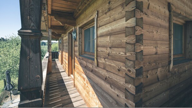 A wooden cabin with a porch, windows, and a view of greenery. - Holiday Home 'Kaiser' with Mountain View, Private Terrace and Wi-Fi (Aßling)