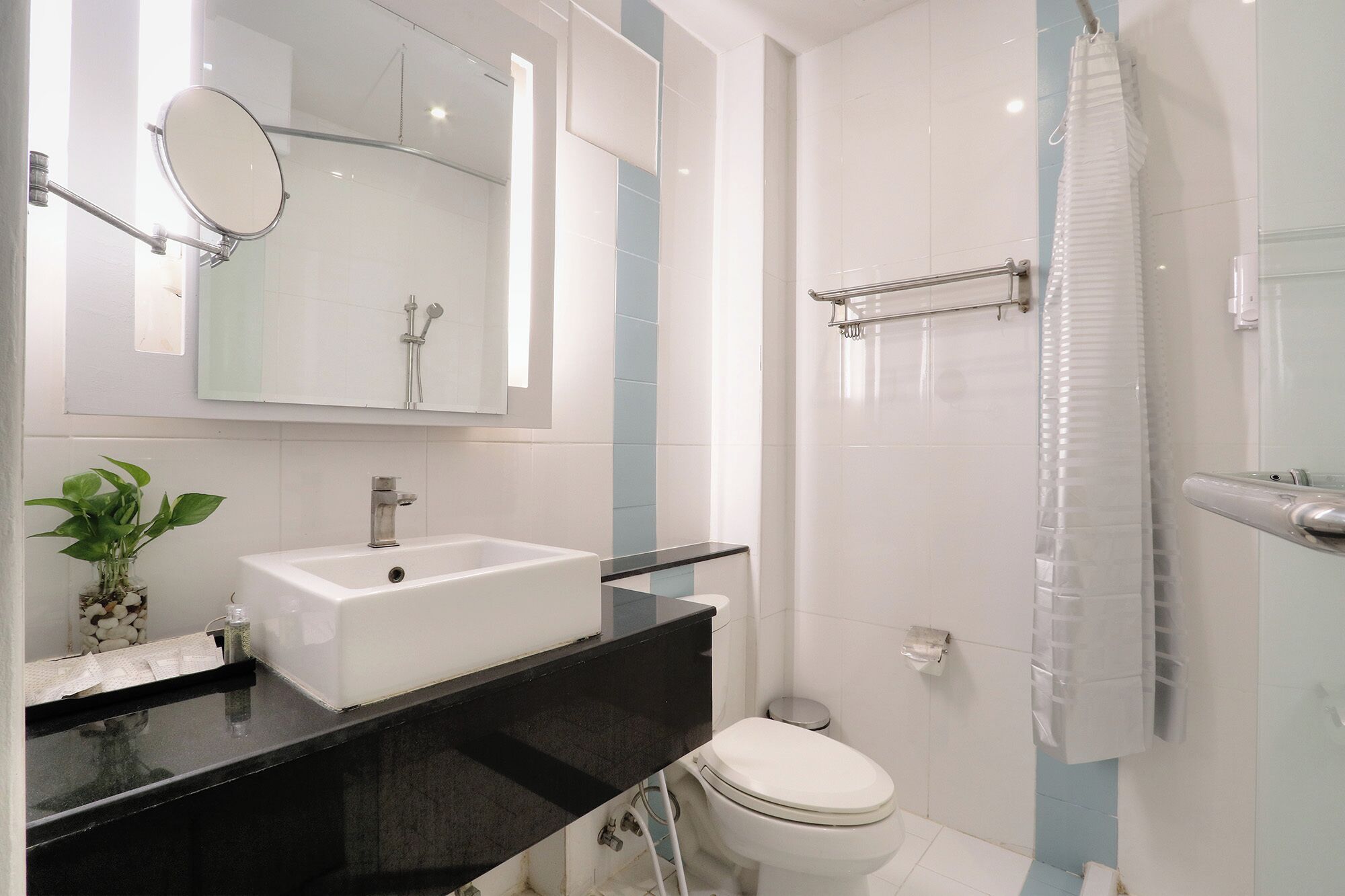 A modern bathroom with a white sink, a mirror, a shower, and a toilet.