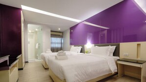 Een hotelkamer met een groot bed, een nachtkastje, een bureau en een douche.