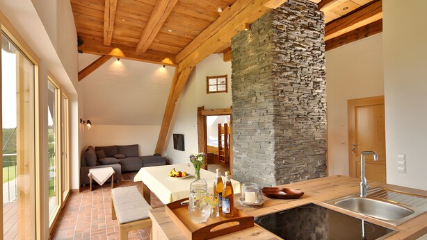 Une cuisine moderne avec une colonne en pierre, des poutres en bois, une grande fenêtre et une cuisinière intégrée.