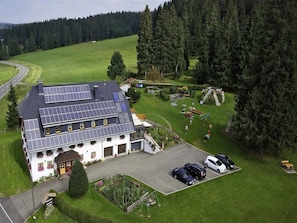 Ein Gebäude mit Solaranlage, Parkplatz und grüner Landschaft.