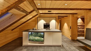 Une cuisine moderne dotée d’un téléviseur encastré, de murs en bois et d’un plafond en pente.
