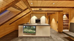 Une cuisine moderne dotée d’un téléviseur encastré, de poutres en bois et offrant une vue sur l’extérieur.