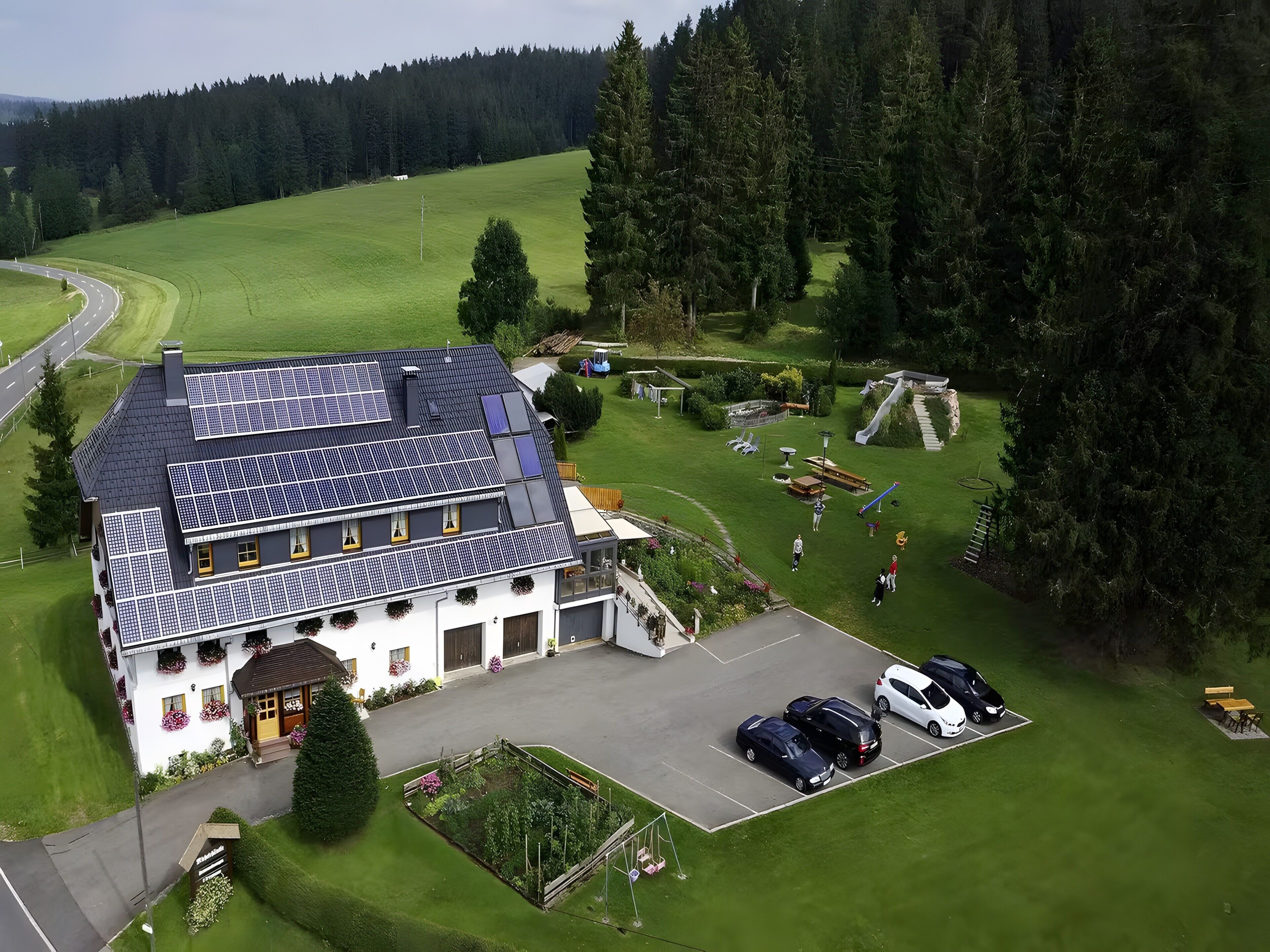 Ein zweistöckiges Gebäude mit Solaranlage, Parkplatz und gepflegtem Rasen.