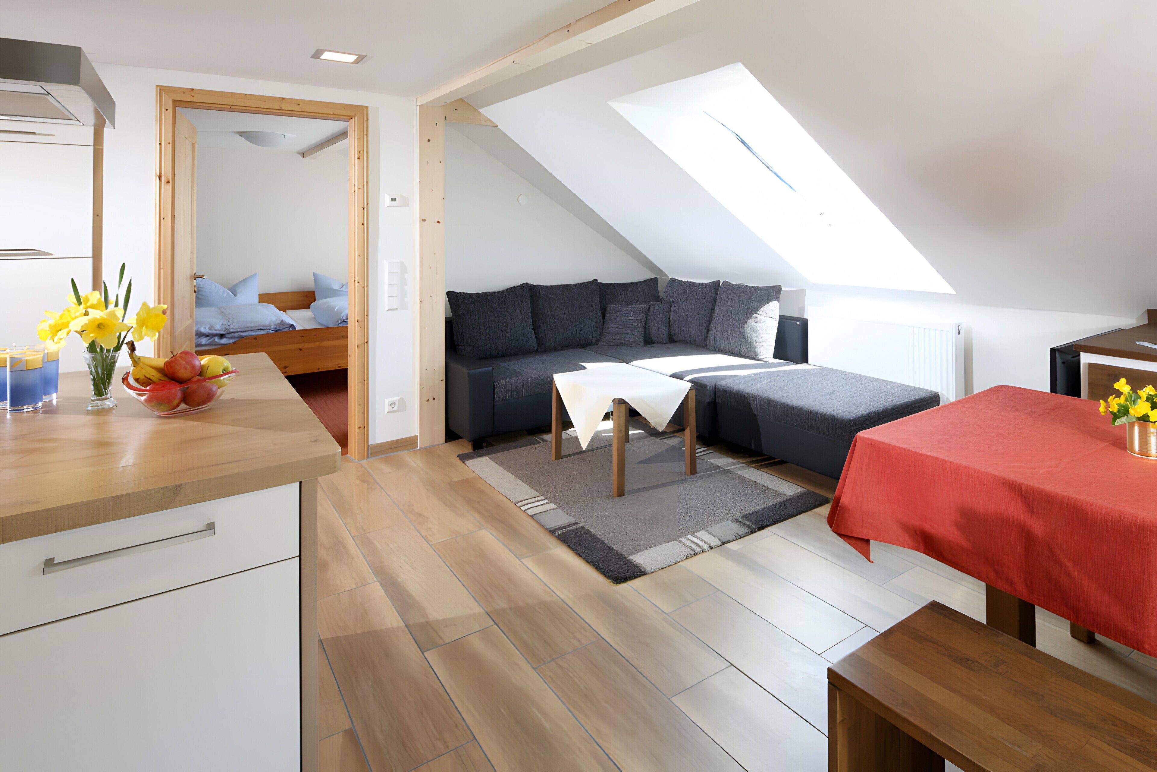 A compact living space with a loft bedroom, a dining area, and a kitchenette.