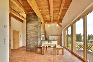 A spacious room with a high ceiling, stone pillar, and large windows.