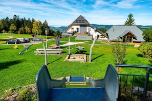 A residential property with a large house, a garage, a patio area, and a playground.