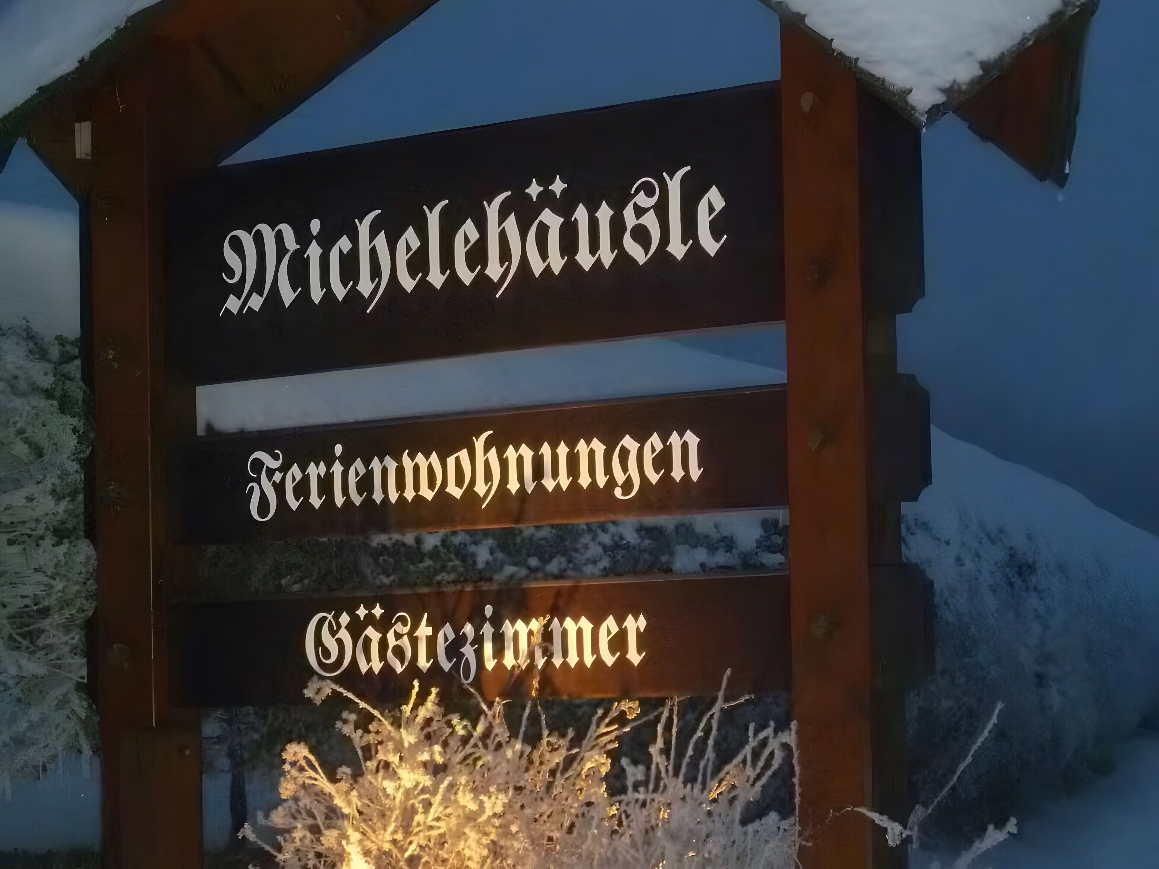 A wooden sign with the text 'Michelehausle Ferienwohnungen Gästezimmer.'
