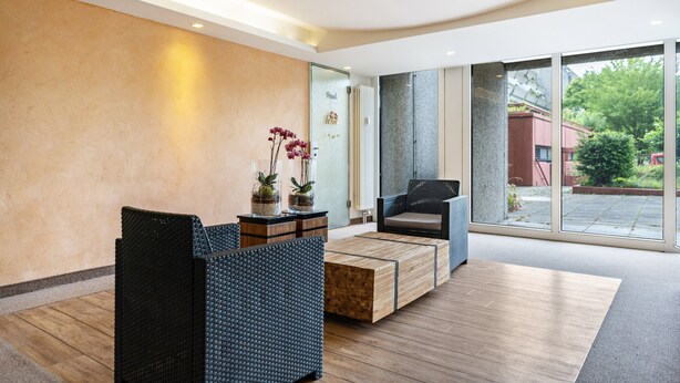 A modern lobby with a reception desk, seating area, and large windows offering a view of the outdoors.