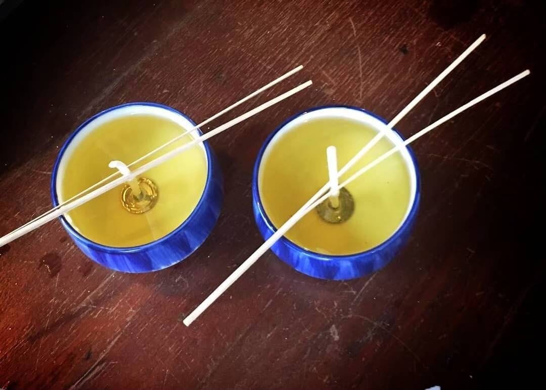 Zwei blaue Kerzenständer mit weißen Stäbchen auf einer Holzoberfläche.