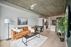 Un salon moderne avec un canapé, une table basse et un tableau accroché au mur.