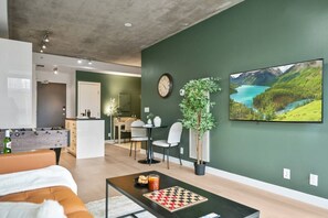Un salon moderne agrémenté d’un baby-foot, d’un jeu d’échecs et d’un grand tableau représentant un paysage.