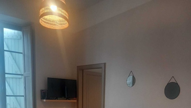 Huoneessa on puulattia, hyllyllä televisio, ovi ja kuviollinen matto.