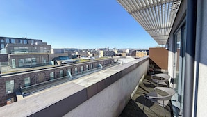 Terraço no telhado com vista para a cidade, uma pérgola e área de estar externa.