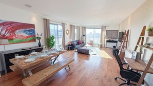 Uma sala de estar espaçosa com área de jantar, um sofá, uma mesa de centro e um quadro na parede.