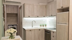 Una cuina moderna amb armaris de fusta clara, taulell blanc, forn integrat i rentamiques d'acer inoxidable.