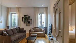 A modern living room with a brown sofa, a beige sofa, and a coffee table. There is a TV on a stand and a plant on the wall. - ISIDORO E PERLA FLORENCE SUITES (Firenze)
