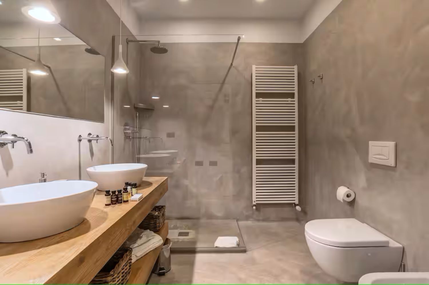 Un baño moderno con dos lavamanos grandes blancos, una ducha y un inodoro.