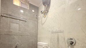 Casa de banho com sanita, chuveiro e secador de mãos fixado na parede.