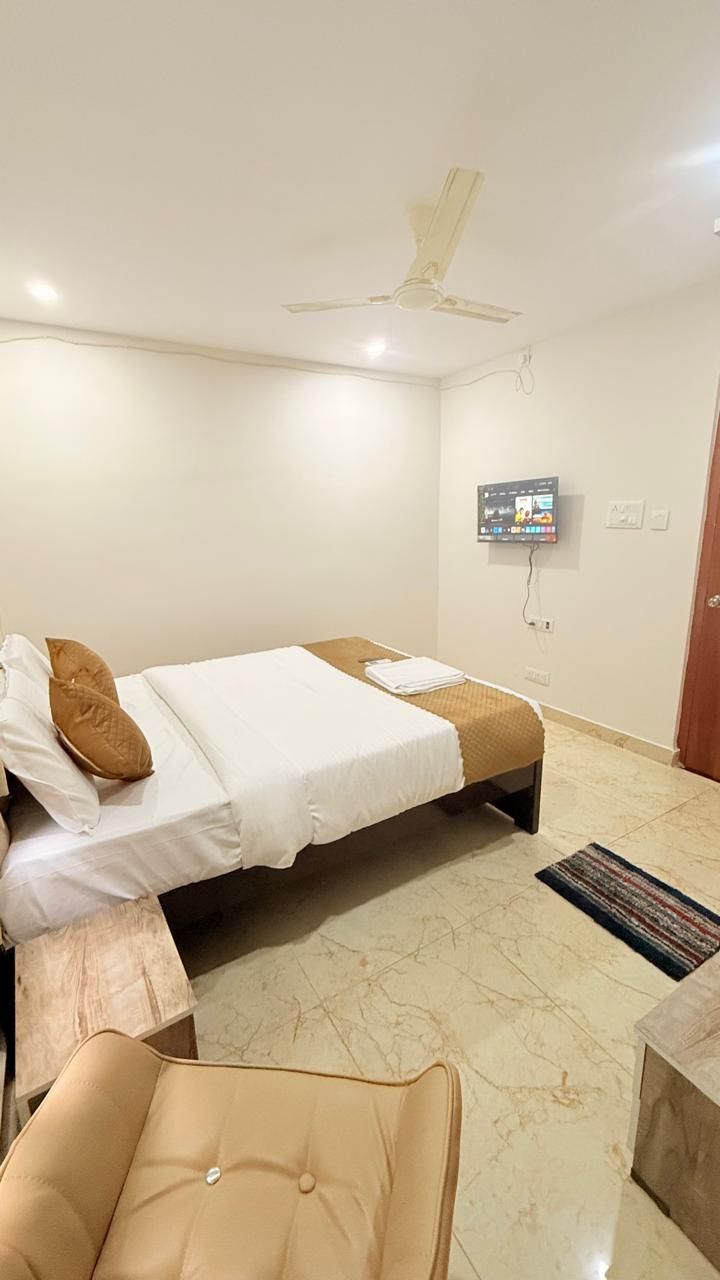 Una habitación de hotel con una cama, una silla, un televisor y un ventilador de techo.