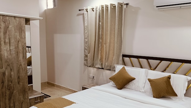 Uma cama bem arrumada com um controle remoto, um cobertor acolchoado marrom e dois travesseiros.