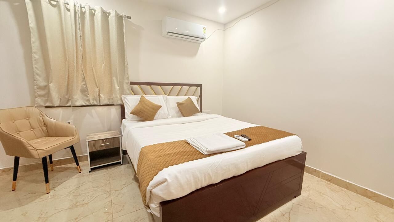 Una habitación de hotel con una cama, una silla, una mesita de noche y un equipo de aire acondicionado.