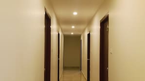 Um corredor comprido e estreito com chão de mármore e portas de madeira em ambos os lados.