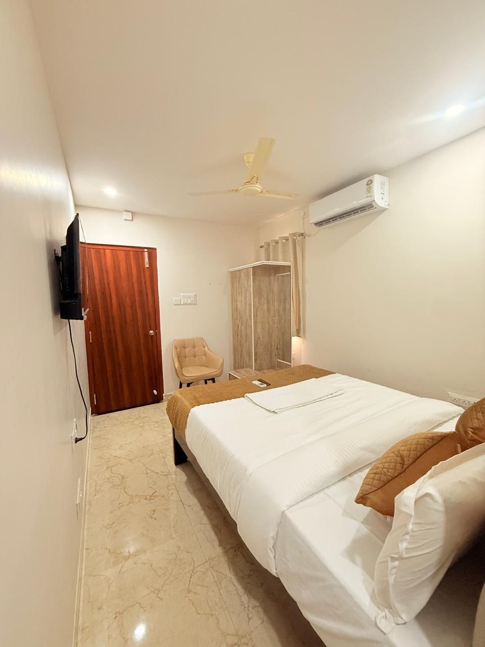 Une chambre d’hôtel équipée d’un lit, d’une chaise, d’un téléviseur, d’un appareil de climatisation et d’une porte en bois.