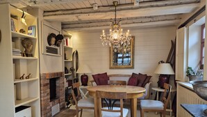 Un'accogliente sala da pranzo con un tavolo rotondo in legno, sedie imbottite, un camino in mattoni e un lampadario.