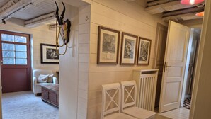Una stanza con una parete in legno bianco, una sedia bianca, un termosifone e quadri appesi.