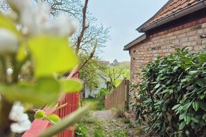 Stroll through the serene garden, surrounded by lush plants and a charming brick building with a pitched roof.