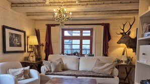 Un soggiorno accogliente con un divano bianco, un tavolino in legno, un lampadario e un esemplare di cervo appeso al muro.