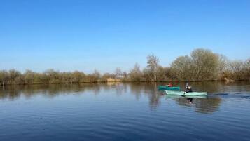 A calm river with two kayaks, one with a person paddling and another stationary.
