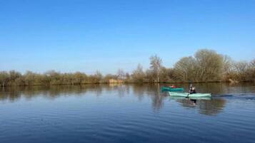 A calm river with two kayaks, one with a person paddling and another stationary.