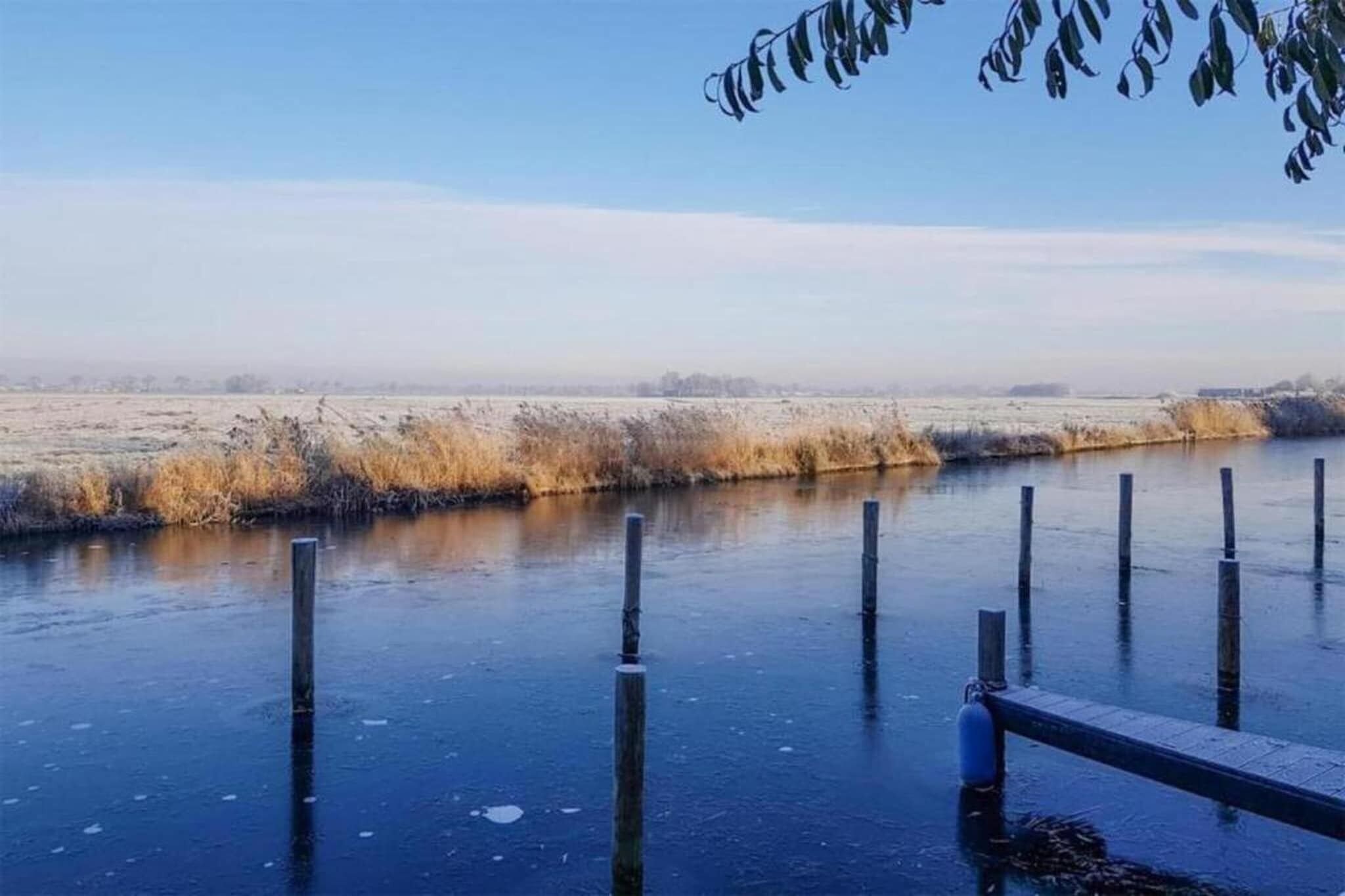 A frozen river with wooden posts and a metal railing.