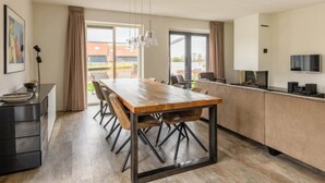 A modern kitchen with a wooden table, black chairs, and a built-in oven. - Holiday home in Langelille near Lake (Langelille)