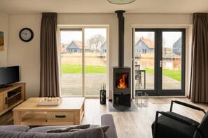 A living room with a fireplace, a television, and a sofa. - Holiday home in Langelille for family (Langelille)