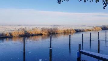 A frozen river with wooden posts and a metal railing.