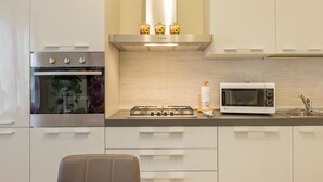 Une cuisine moderne équipée d’un four encastré, d’une cuisinière à gaz, d’un four à micro-ondes et d’un évier en acier inoxydable.