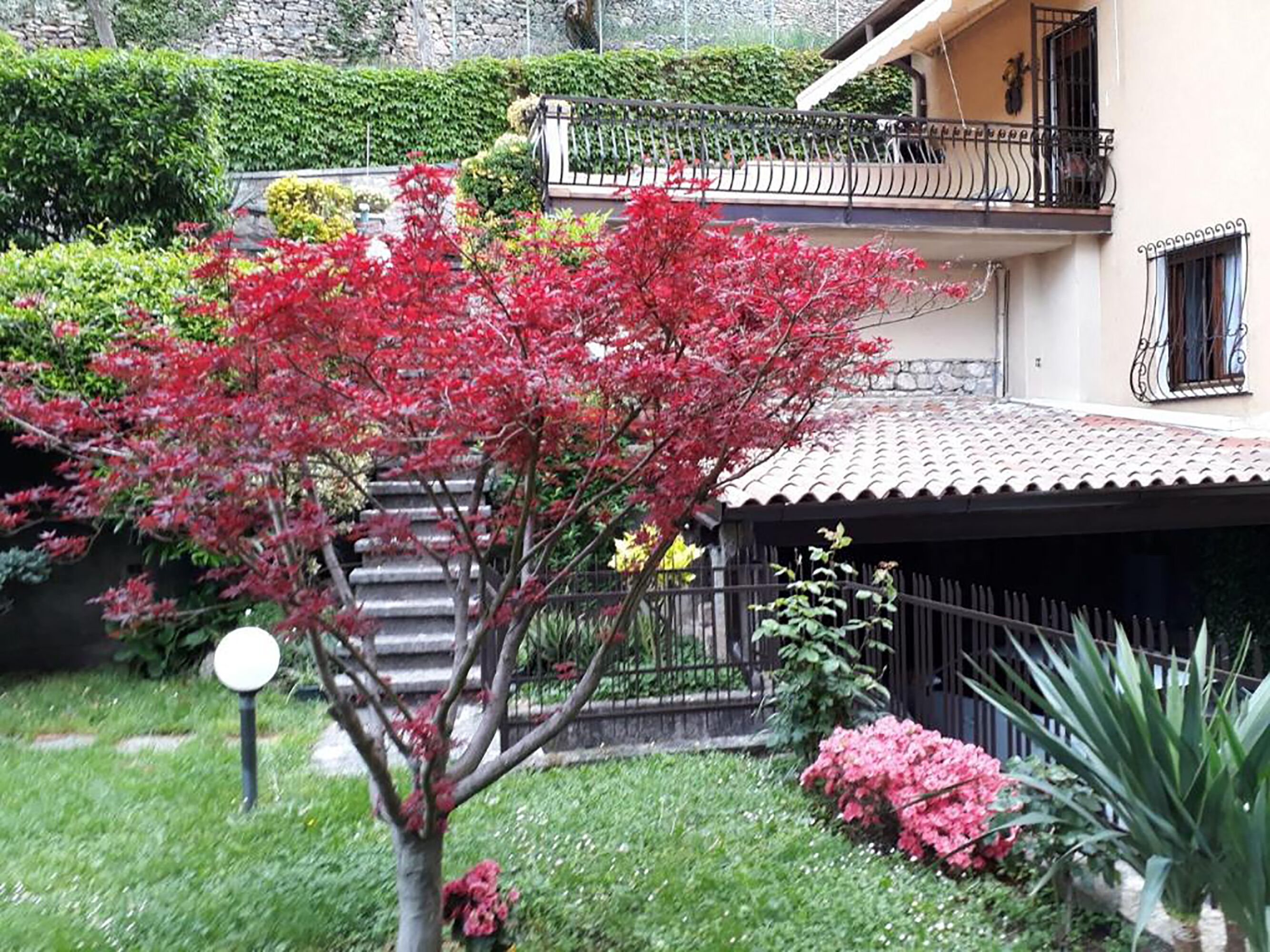 A house with a garden, a balcony, and a stone wall.