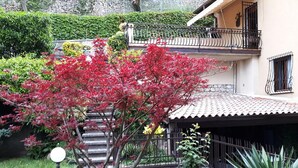 Une maison avec un jardin, un balcon et un mur en pierre.