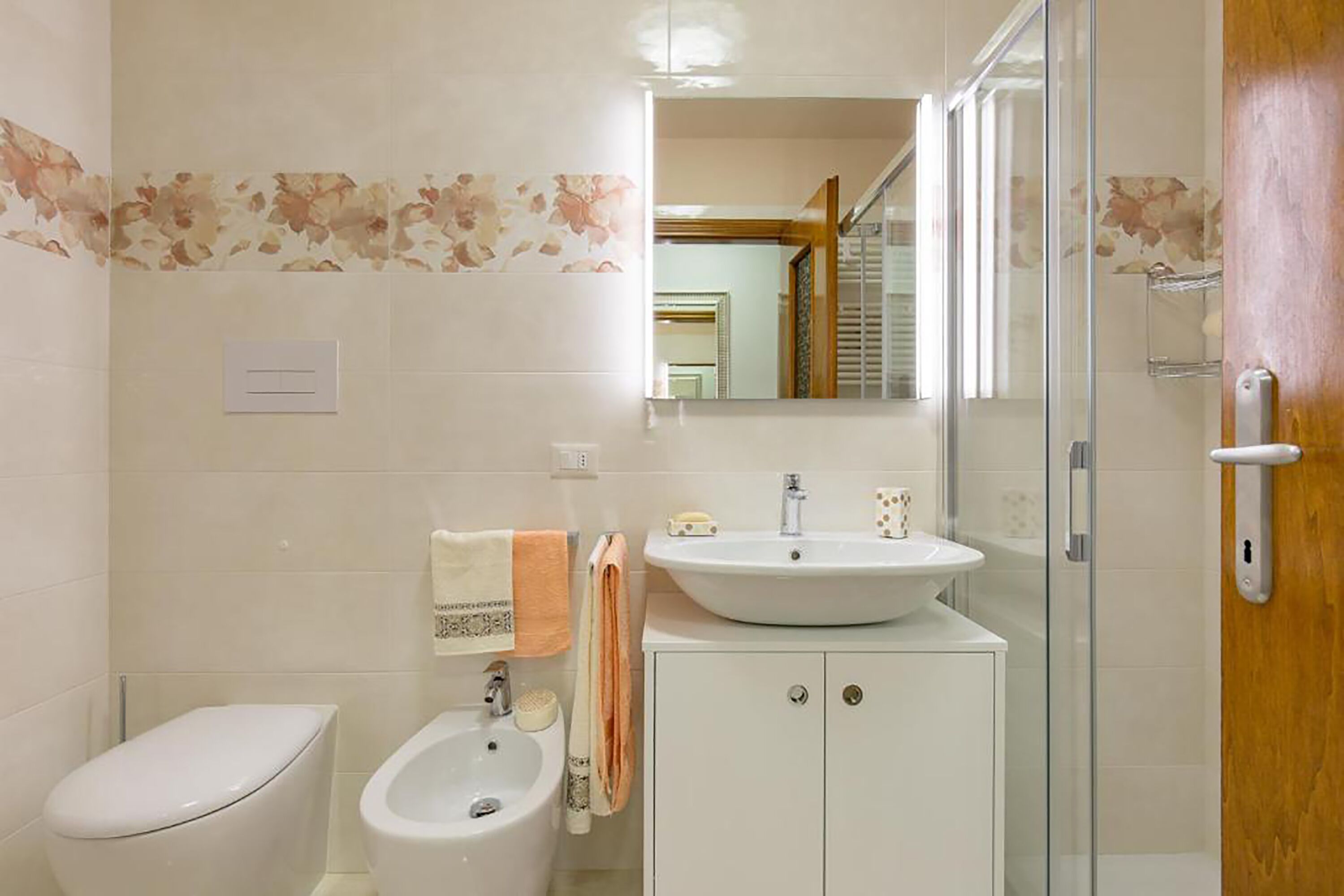 Une salle de bain comprenant des toilettes, un bidet, un lavabo et une douche à parois de verre.