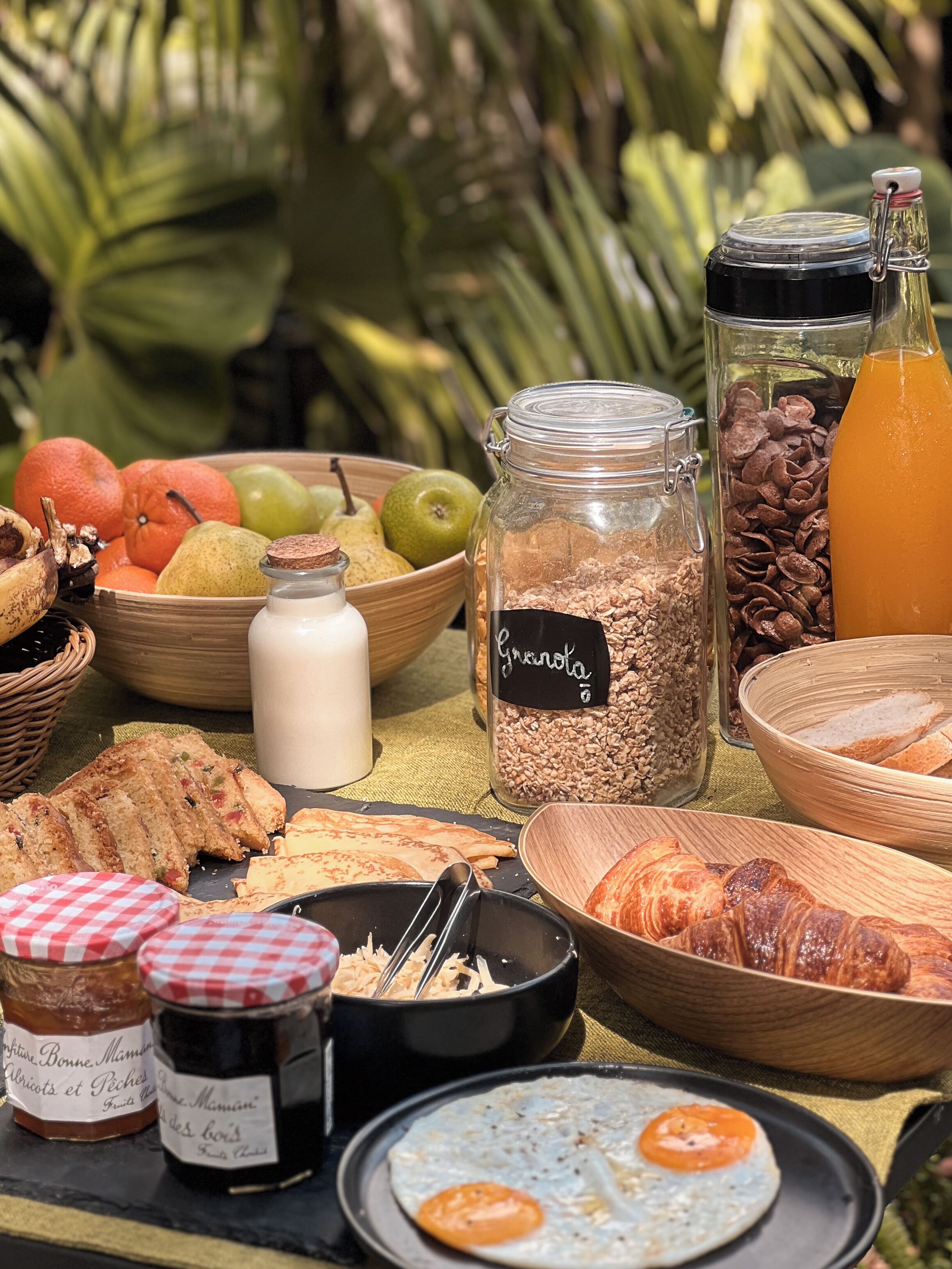 A breakfast buffet with various food items including fruits, granola, pastries, and condiments.