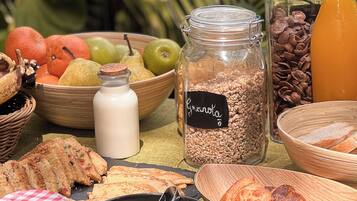 A breakfast buffet with various food items including fruits, granola, pastries, and condiments.