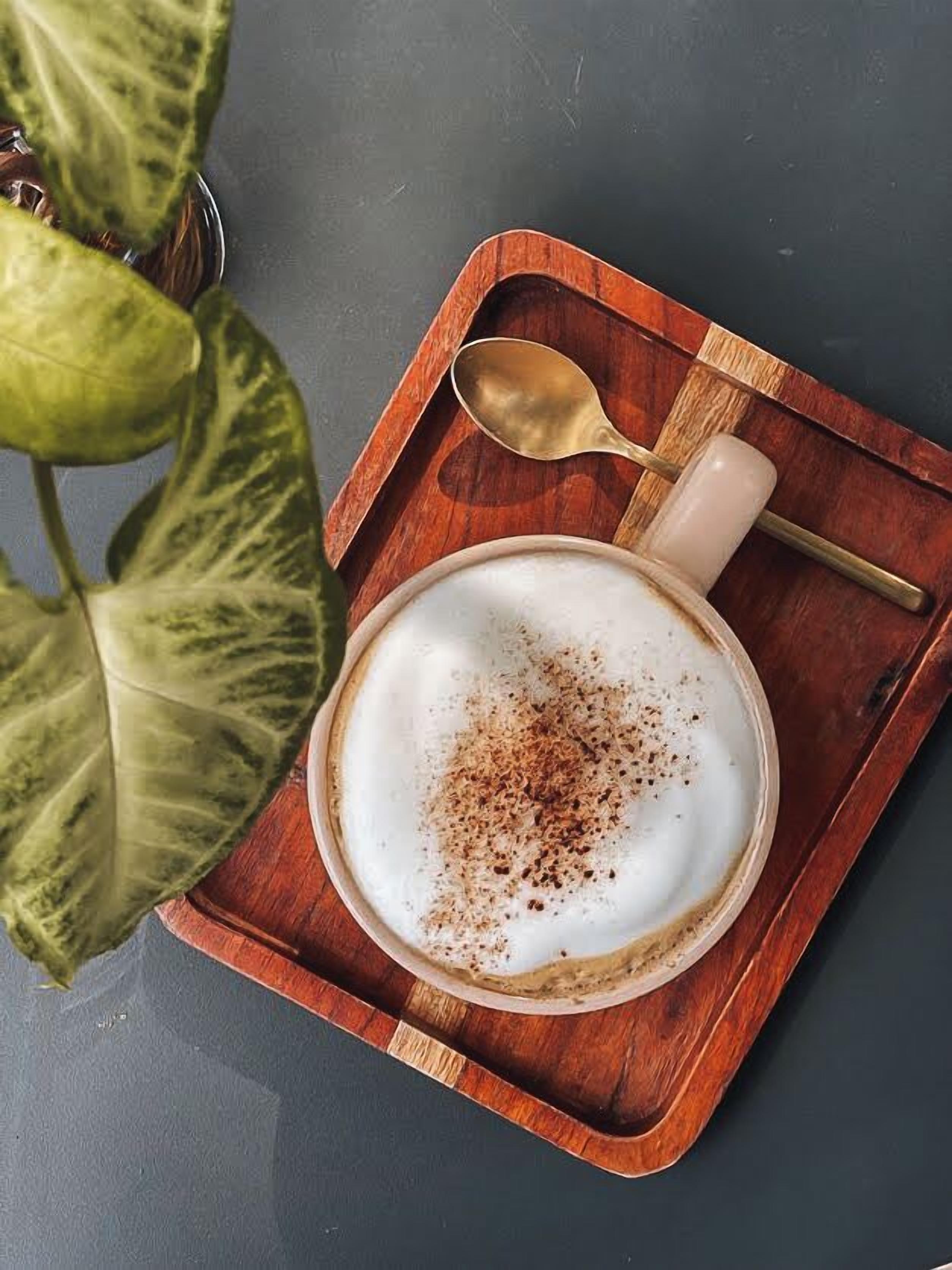 Una taza de café con una cuchara sobre una bandeja de madera.