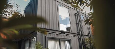 Un edificio moderno con ventanas amplias y techo plano, rodeado de vegetación.