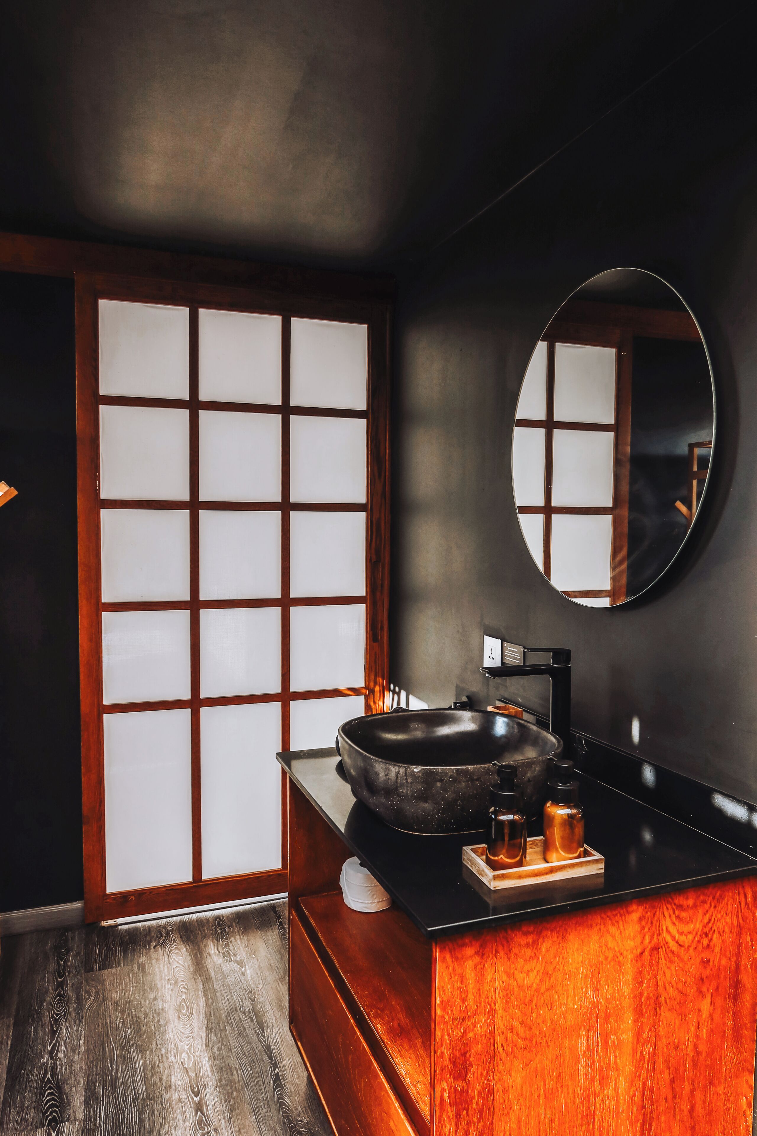 A modern bathroom with a black sink, wooden vanity, and a large mirror.