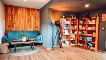 Una habitación con un sofá azul, una mesa de centro de madera, una lámpara de pie y dos estanterías de madera llenas de libros.