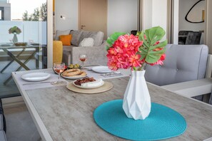 A dining table set with plates, glasses, and a vase of flowers. - Mulberry Court Premium Apartments (Limassol)